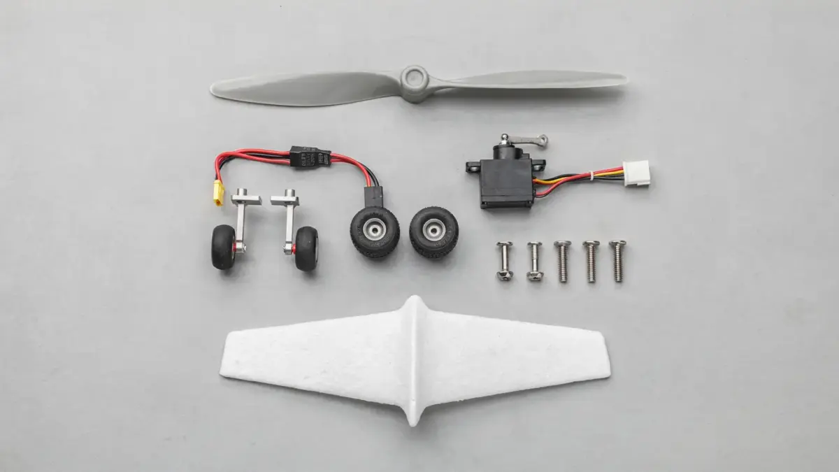 RC Flugzeug Ersatzteile auf einer Werkbank: Propeller, Servo, Fahrwerk und andere wichtige Teile