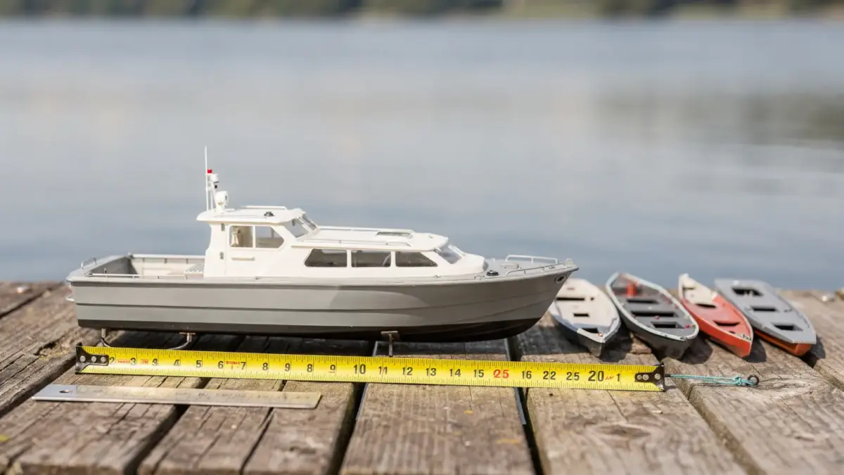 RC Boot Größe: Modellboote in verschiedenen Längen mit Maßband am Ufer
