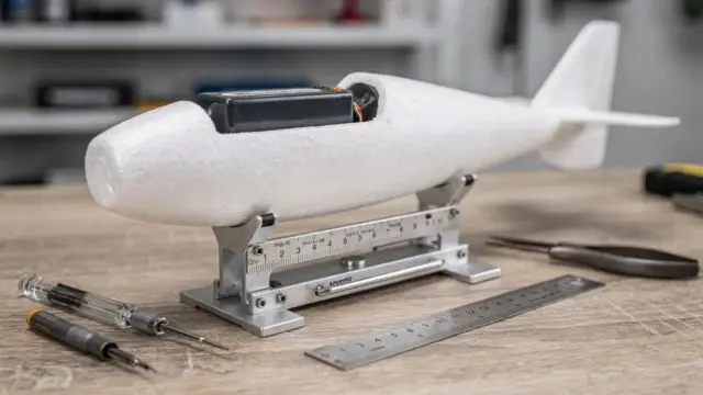 RC-Schwerpunkt-Prüfung am Modellflugzeug auf der Werkbank mit Waage und Messwerkzeug